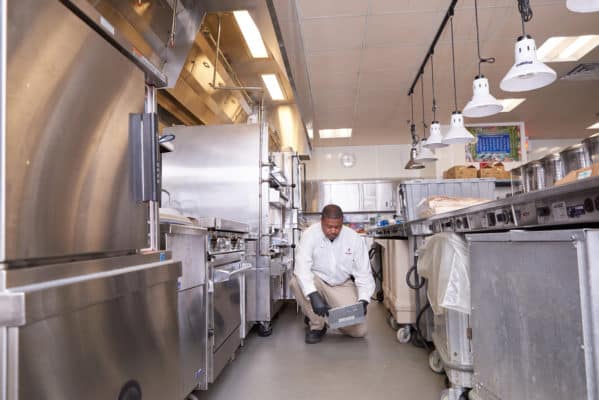 Modern Service Professional servicing a trap in a commercial kitcheni