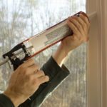 man caulking window during the day
